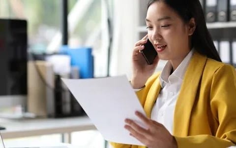 Professional woman on phone holding document in office